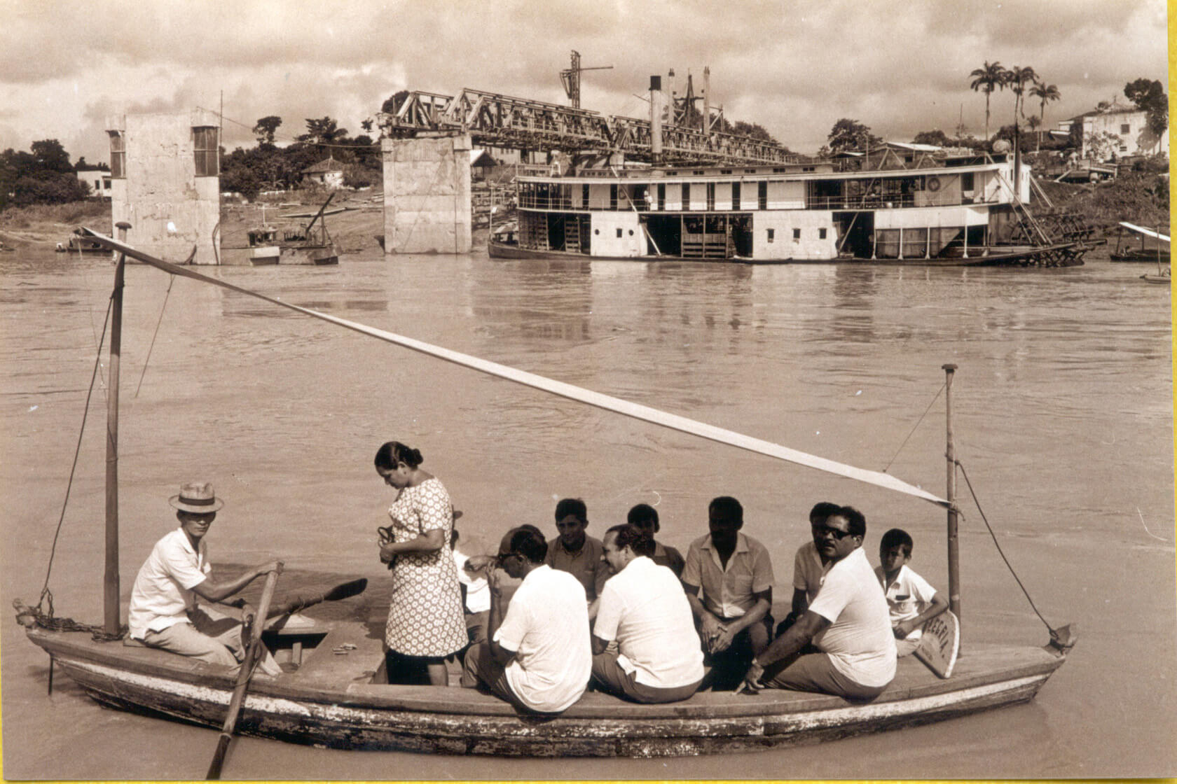 Catraia, meio de transporte popular para travessia do rio Acre. Ao fundo, vista da construção da ponte Juscelino Kubitschek, Década de 60